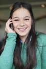 Nahaufnahme eines lächelnden Mädchens, das mit dem Handy spricht und wegschaut — Stockfoto