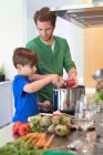 Boy assisting his father in the kitchen — Stock Photo