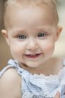 Gros plan de bébé fille aux yeux bleus souriant — Photo de stock