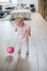 Niña alegre jugando con la pelota en casa - foto de stock