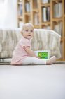 Bebé jugando con juguete bloque musical en el suelo en casa - foto de stock