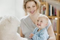 Smiling woman playing with happy baby daughter at home — Stock Photo