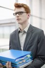 Young redheaded businessman holding files in office — Stock Photo