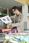Male fashion designer holding sketches in office — Stock Photo
