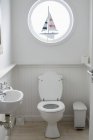 Intérieur de petite salle de bain blanche avec fenêtre ronde — Photo de stock