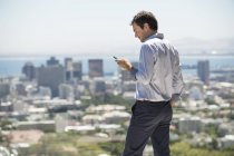 Чоловік стоїть на терасі в місті і використовує мобільний телефон — стокове фото