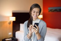 Sorrindo mulher elegante usando telefone celular no quarto de hotel — Fotografia de Stock