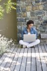 Woman sitting on hardwood floor and using laptop in countryside — Stock Photo