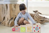 Мила дівчинка грає з вкладеними кубиками вдома — стокове фото