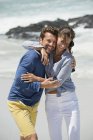 Glückliches Paar am Strand mit welligem Meer im Hintergrund — Stockfoto