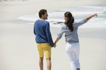 Paar läuft Händchen haltend am Sandstrand — Stockfoto