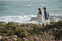 Resting couple walking on sea coast holding hands — Stock Photo