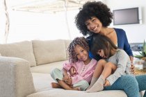 Mulher sorridente sentada com suas duas filhas — Fotografia de Stock