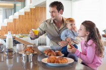 Family having breakfast at a kitchen counter — Stock Photo