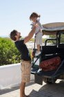 Homem brincando com sua filha ao lado de um SUV — Fotografia de Stock