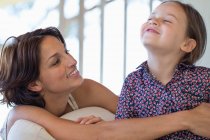 Donna sorridente con la figlia a casa — Foto stock