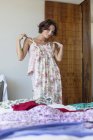 Frau probiert gemustertes Kleid zu Hause im Schlafzimmer an — Stockfoto