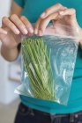 Close-up de mãos femininas que empacotam verduras de folha do armazenamento — Fotografia de Stock