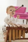 Cheerful baby boy playing xylophone on carpet — Stock Photo