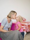 Cute young mother and daughter kissing at home — Stock Photo