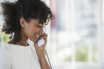 Усміхнена жінка говорить по стаціонарному телефону — стокове фото