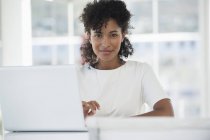 Porträt einer Frau, die im Büro vor dem Laptop sitzt — Stockfoto