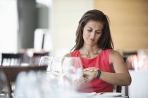 Frau mit Armbanduhr sitzt im Restaurant und checkt Armbanduhr — Stockfoto