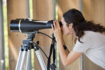 Woman looking through binoculars on tripod — Stock Photo