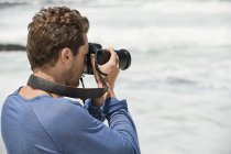 Nahaufnahme eines Mannes mit Kamera, der am Strand fotografiert — Stockfoto