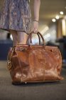 Close-up de mão feminina pegando bolsa de couro de viagem — Fotografia de Stock
