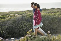 Обнимающая пара, идущая по солнечному побережью — стоковое фото