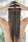 Вид ззаду жінка масажує мокре довге волосся — стокове фото