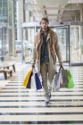 Portrait of young elegant man carrying shopping bags — Stock Photo