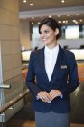 Recepcionista feminina em pé no lobby do hotel e sorrindo — Fotografia de Stock