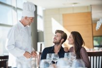 Шеф-повар разговаривает с парой в ресторане — стоковое фото