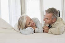 Romantisches Seniorenpaar, das sich auf dem Bett ausruht und einander ansieht — Stockfoto