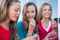 Gros plan de trois filles mangeant du raisin — Photo de stock