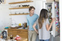 Frau schaut mit Freund in Küche auf Kühlschrank — Stockfoto