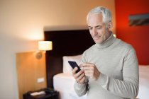 Человек, использующий мобильный телефон в номере отеля — стоковое фото