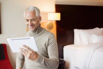 Mann schaut Film auf digitalem Tablet im Hotelzimmer — Stockfoto