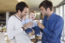 Щасливі батьки ЛГБТ сміються з сином вдома — стокове фото