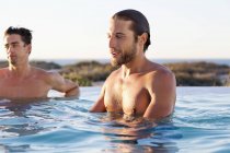 Amigos varones disfrutando en la piscina en la naturaleza - foto de stock
