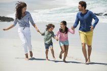 Glückliche Familie, die Händchen haltend am Sandstrand spaziert — Stockfoto