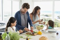 Glückliche Familie bereitet Essen im Küstenhaus zu — Stockfoto
