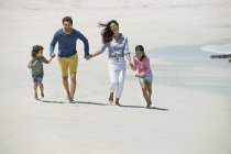 Familia feliz corriendo en la playa de arena - foto de stock
