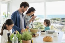 Família feliz preparando comida na casa costeira — Fotografia de Stock