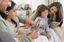 Eltern zeigen Kindern Fotos im Wohnzimmer — Stockfoto