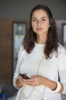Portrait of serious woman standing with mobile phone — Stock Photo