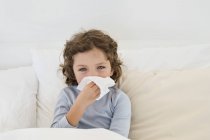 Cute little boy suffering from cold in bed — Stock Photo