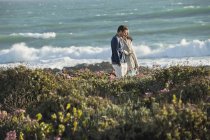 Couple walking in vegetation on sea coast — Stock Photo